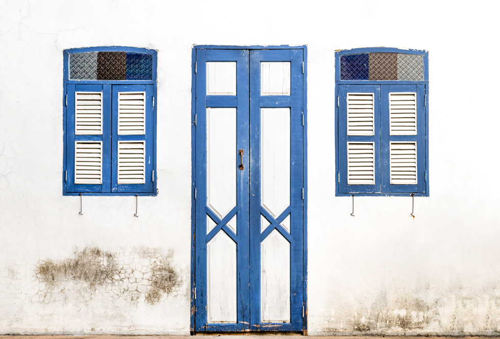 Blue wooden door and window on old white wall background