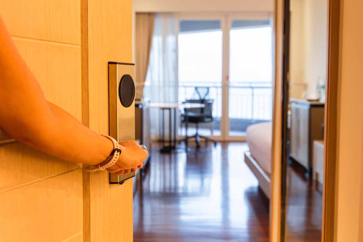 Female hand opening wooden door to hotel room